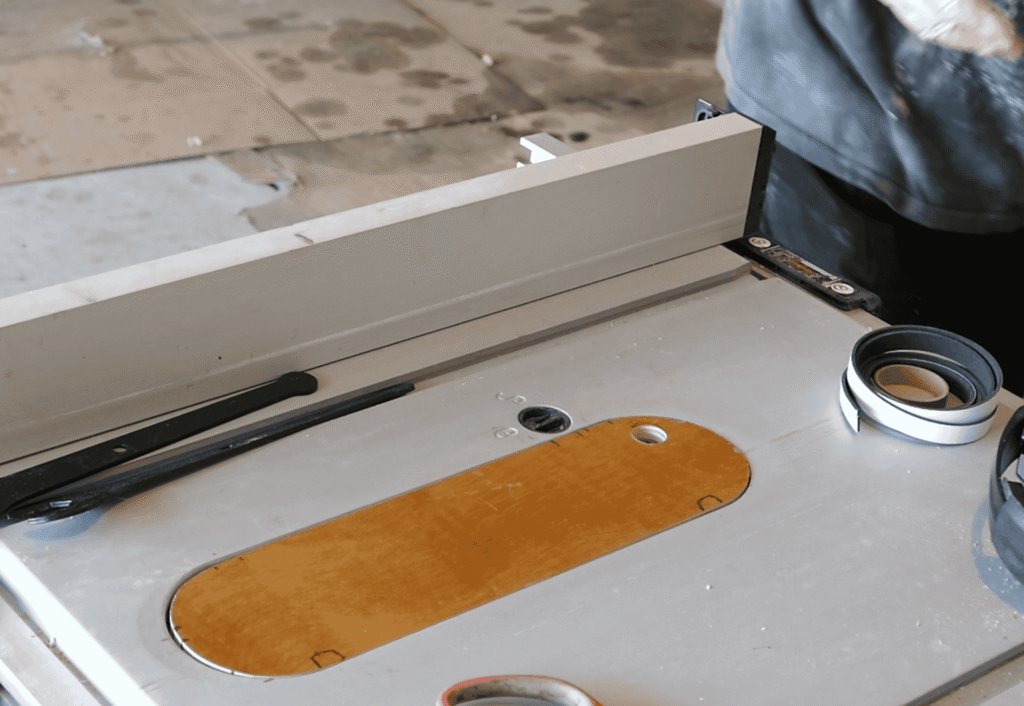 “Close-up of a zero-clearance throat plate on a table saw showing clean, splinter-free wood cuts in a woodworking shop.”